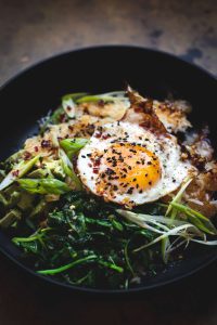 crispy rice bowl with avocado, greens and fried egg